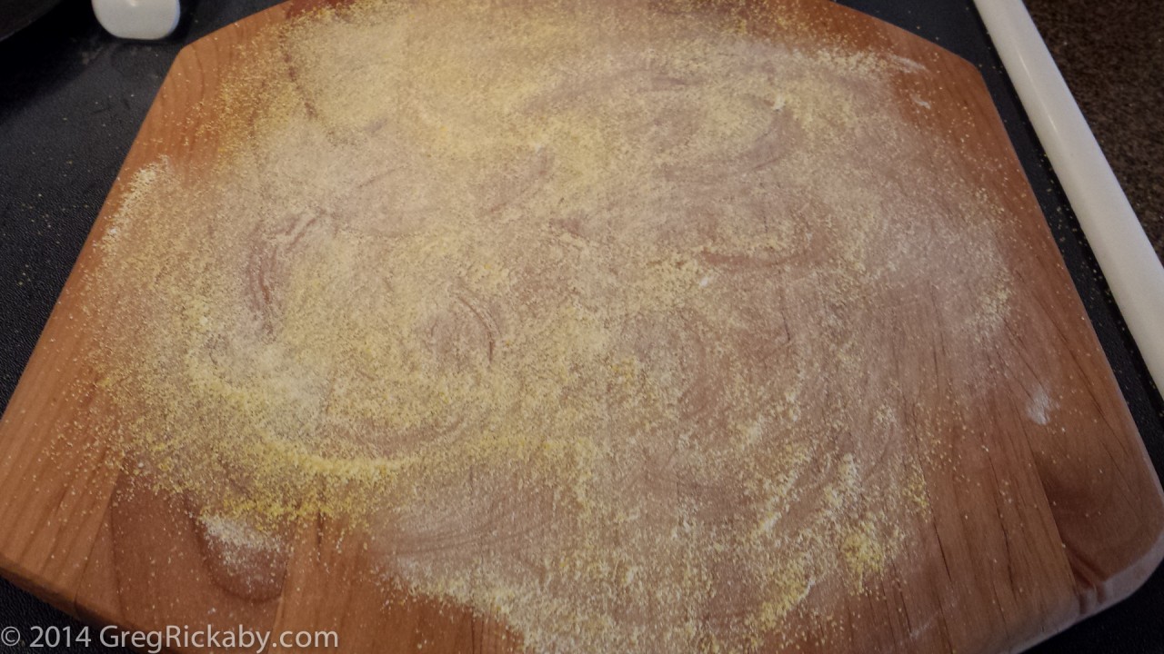 Using your hands, spread the cornmeal and flour until the peel is evenly covered.