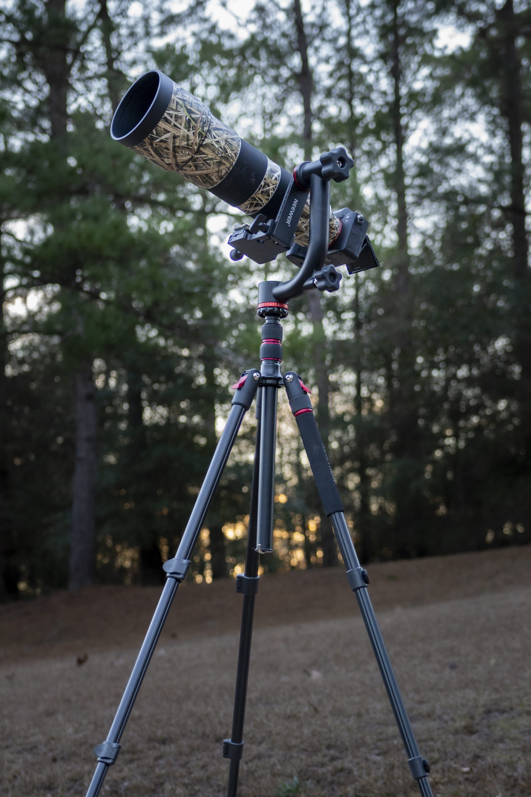 a tripod with a telescope on top of it in front of a wooded area with trees in the background