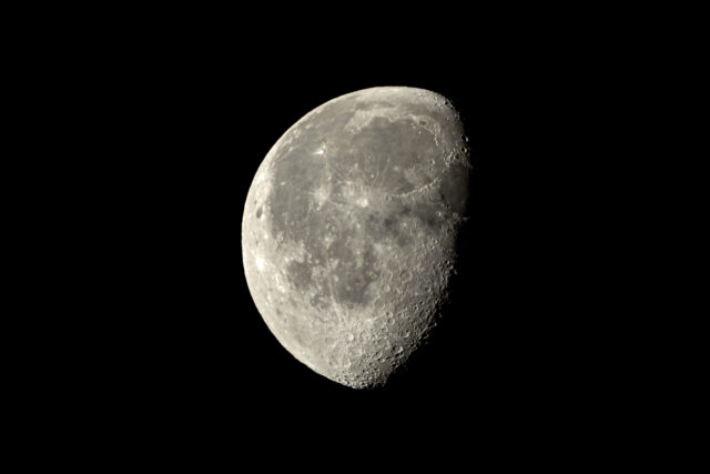 a close up of a half moon in the night sky with a black sky in the background and a dark sky in the foreground